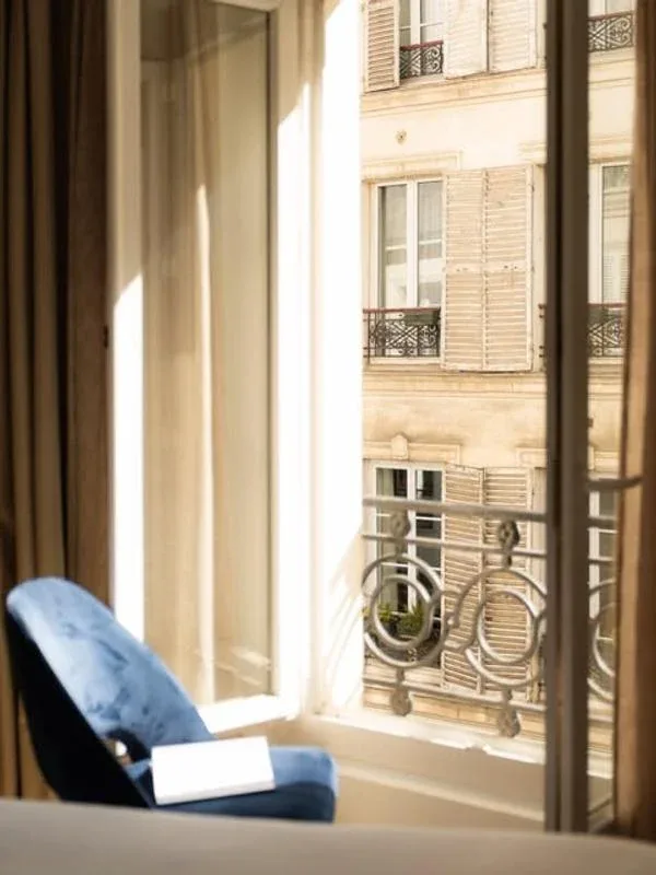 Representative hotel space: A blue upholstered seat sits beside a sunlit window overlooking a building facade.