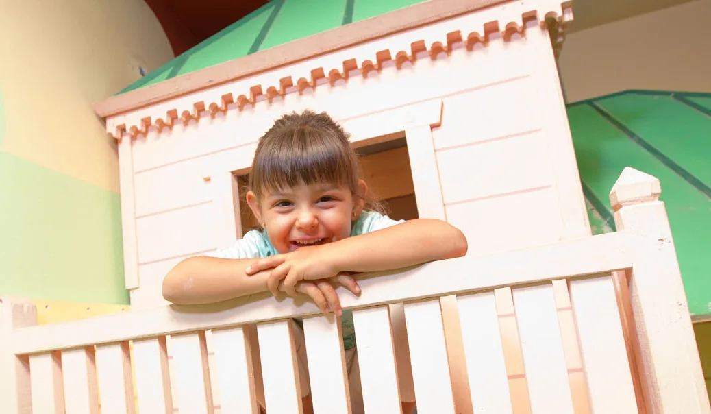 Espacio representativo del hotel: Una niña se apoya sobre la barandilla de una casita de juegos.