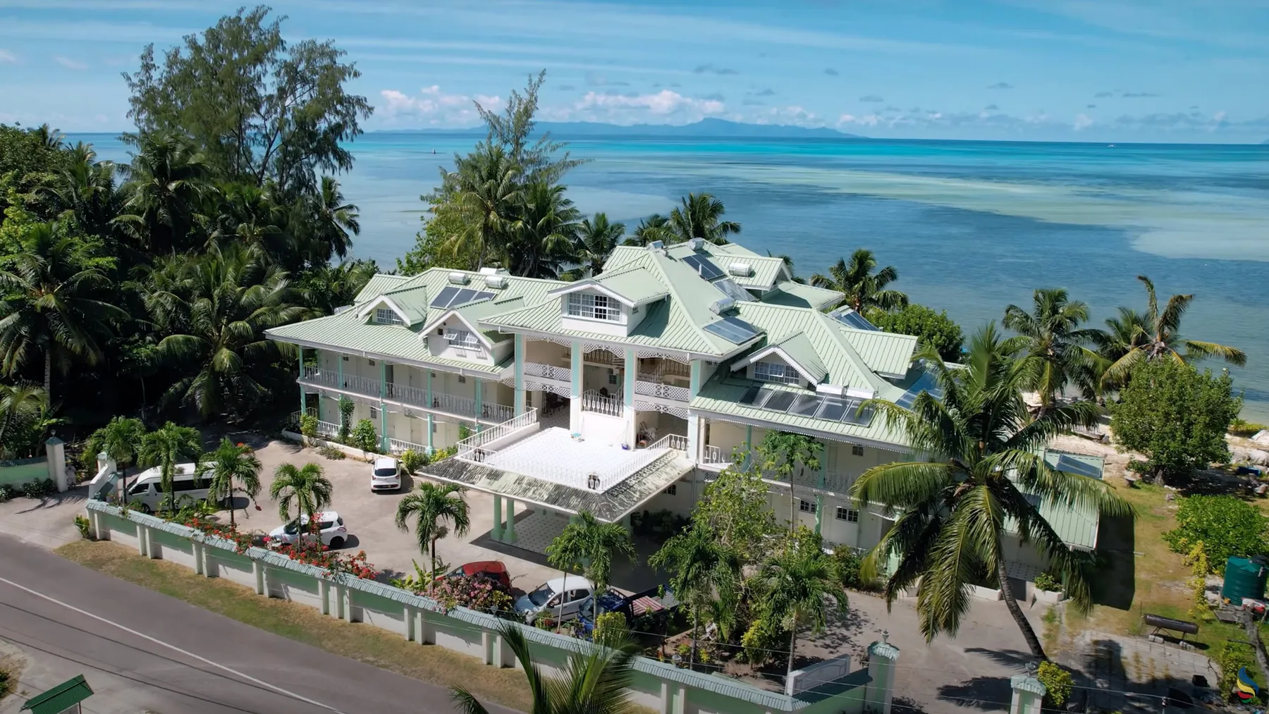 Espacio representativo del hotel: Vista aérea de un edificio grande rodeado de palmeras junto al océano.