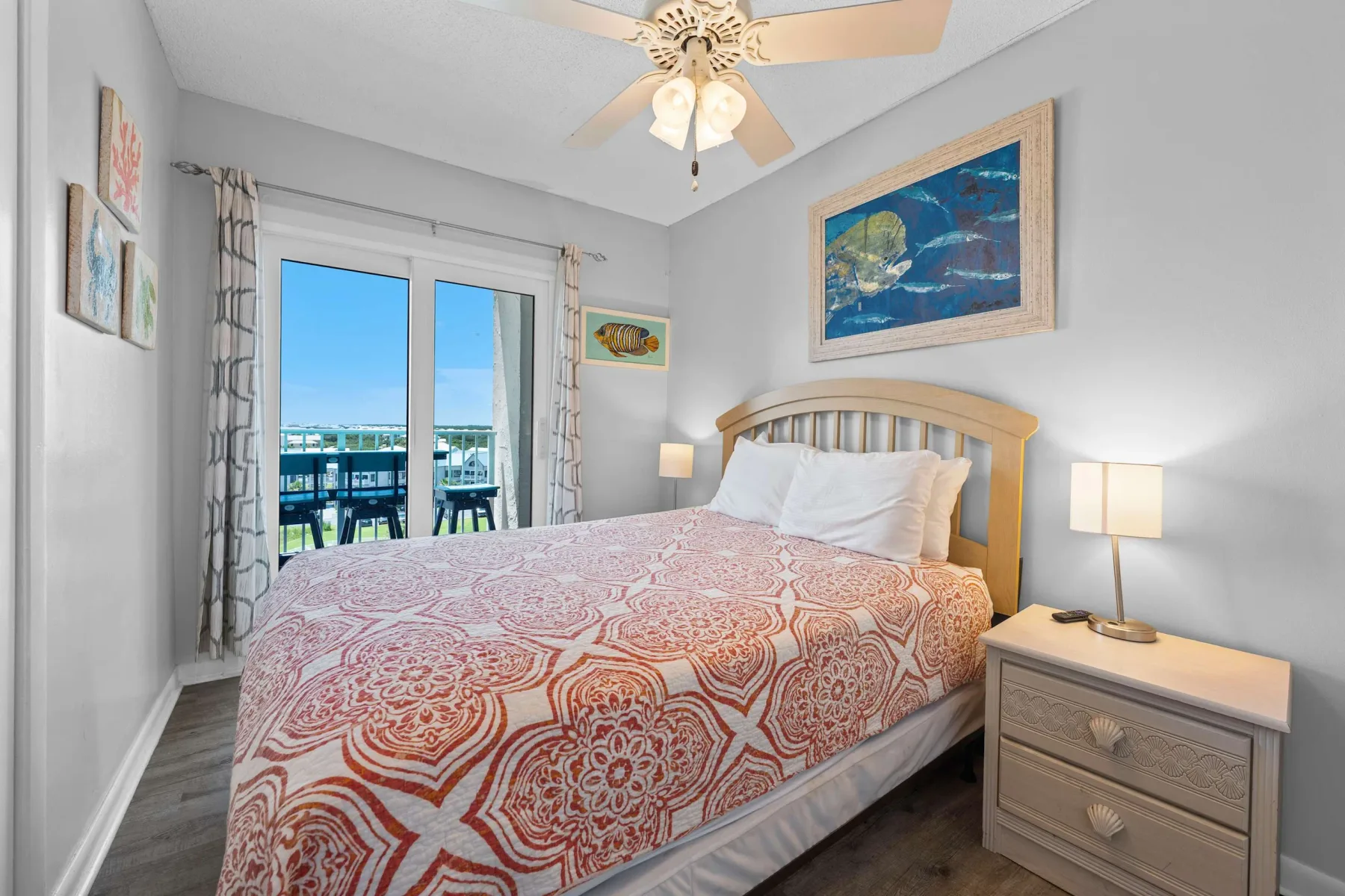 A bedroom with a patterned bedspread and glass doors opening to a balcony.