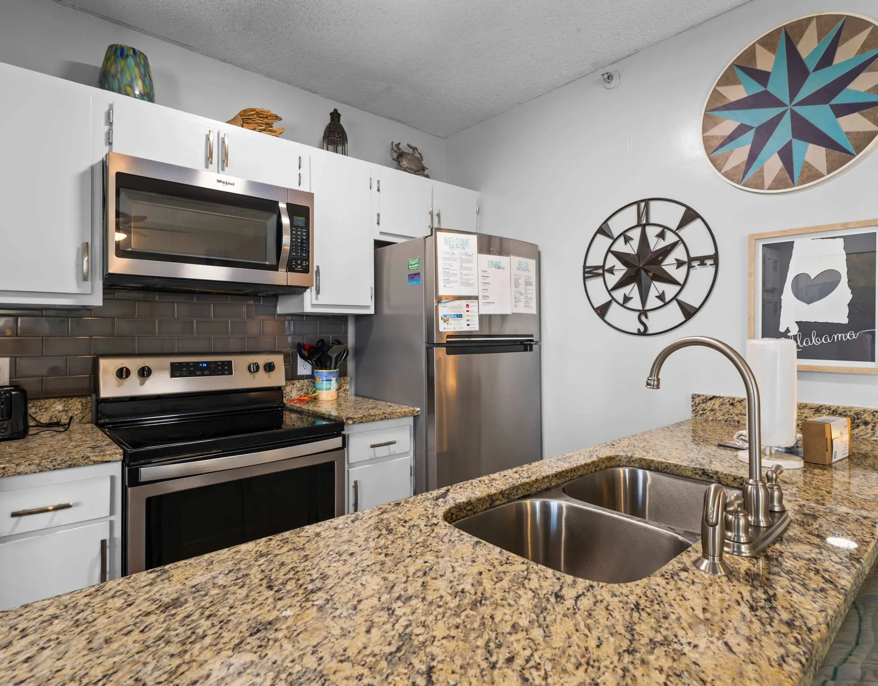 A kitchen with white cabinets, stainless steel appliances, and a sink set into a granite counter.