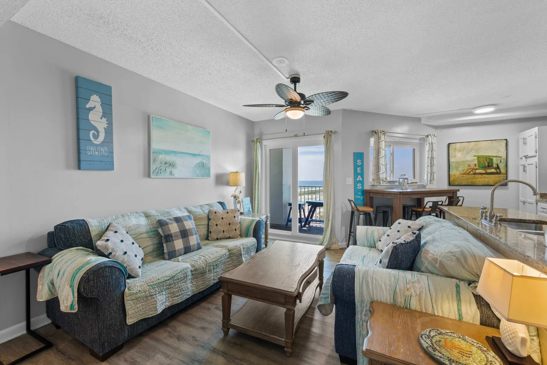 A living room with seating, a coffee table, and a dining area by the windows.