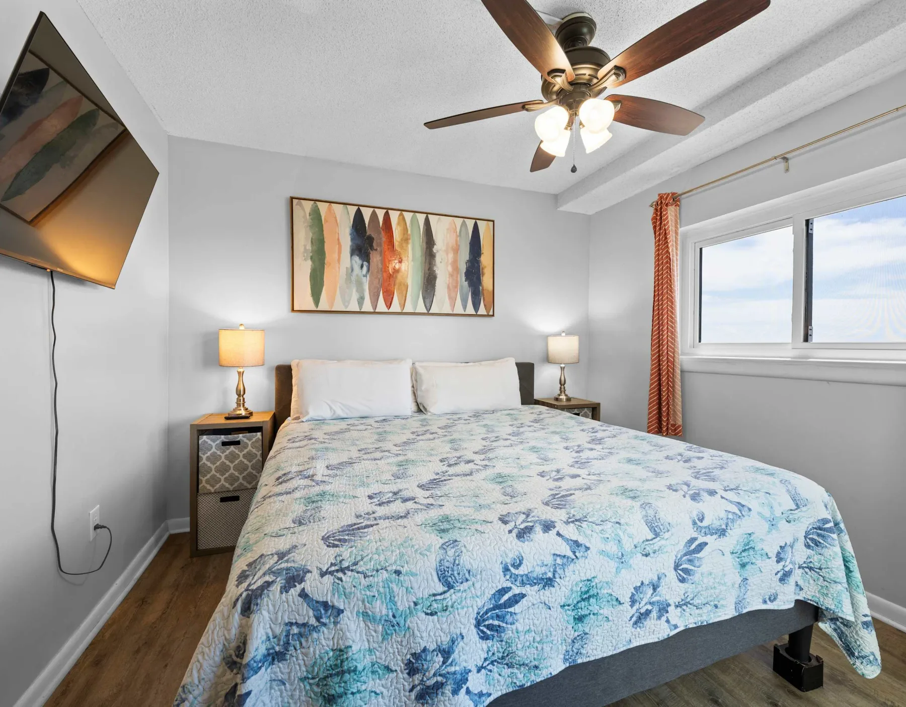 A bedroom with a bed, bedside tables, and a large window.