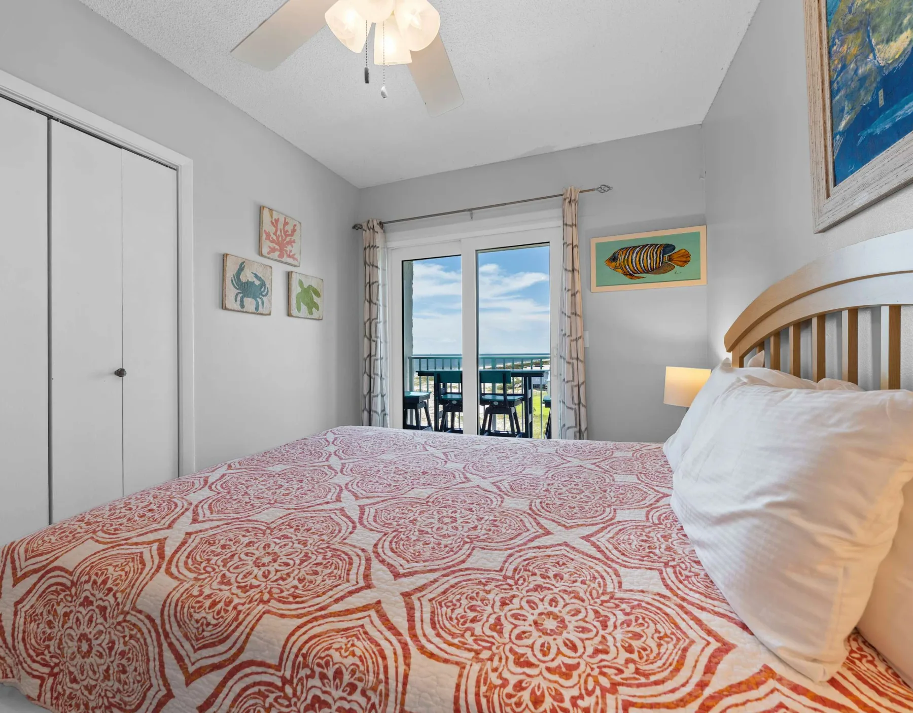 A bedroom with a patterned bedspread and glass doors opening onto a balcony.