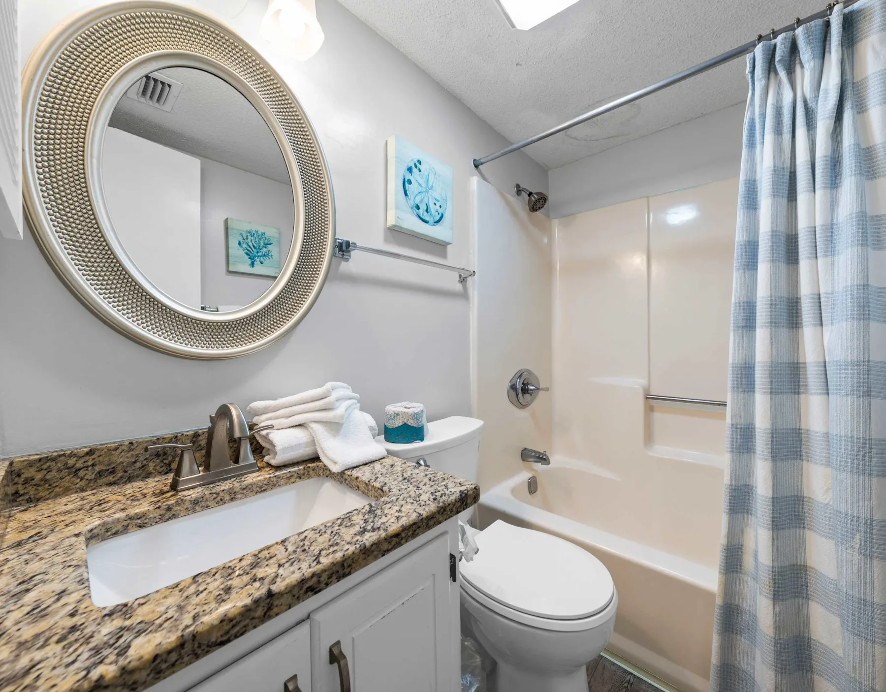 A bathroom with a sink, toilet, and bathtub behind a shower curtain.