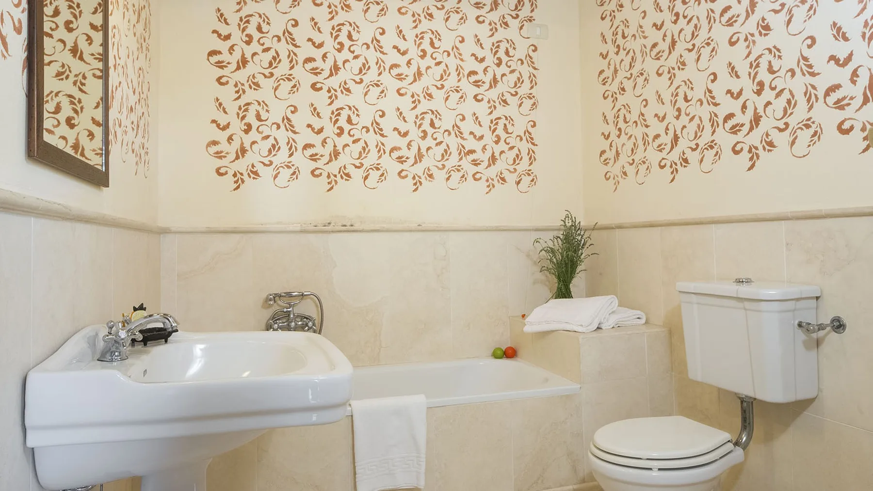 Un baño con bañera, lavabo e inodoro bajo paredes decoradas.
