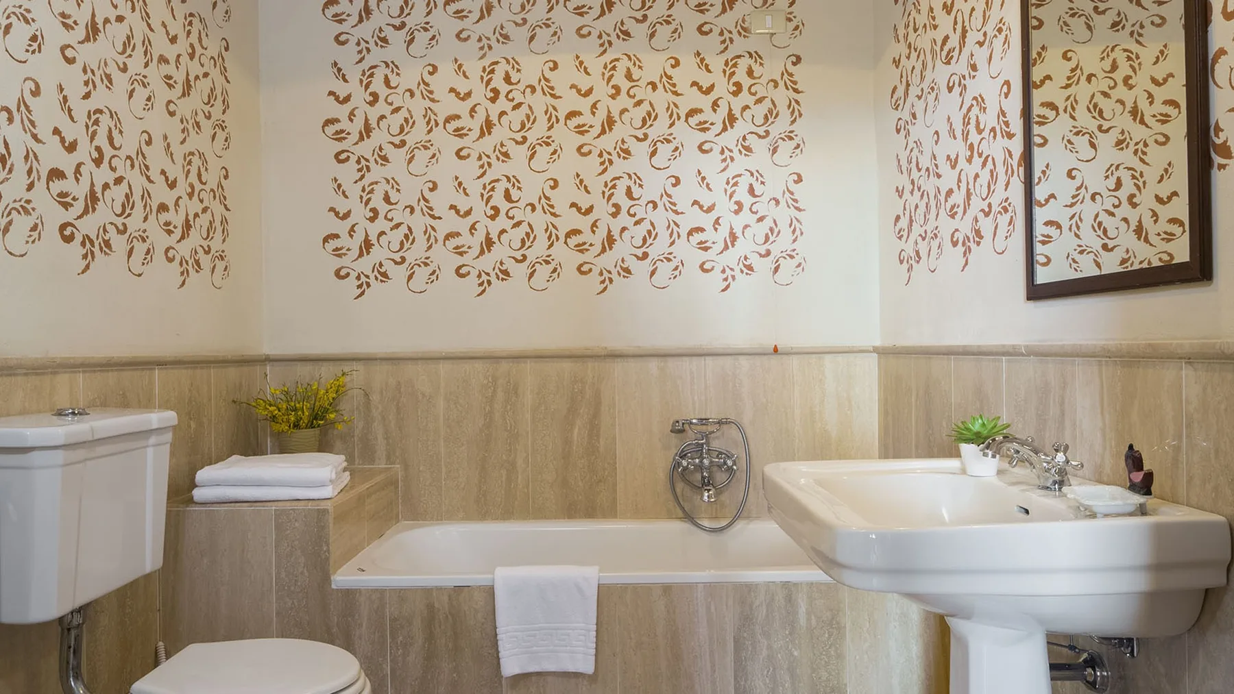 Un baño con bañera, inodoro y lavabo con pedestal.