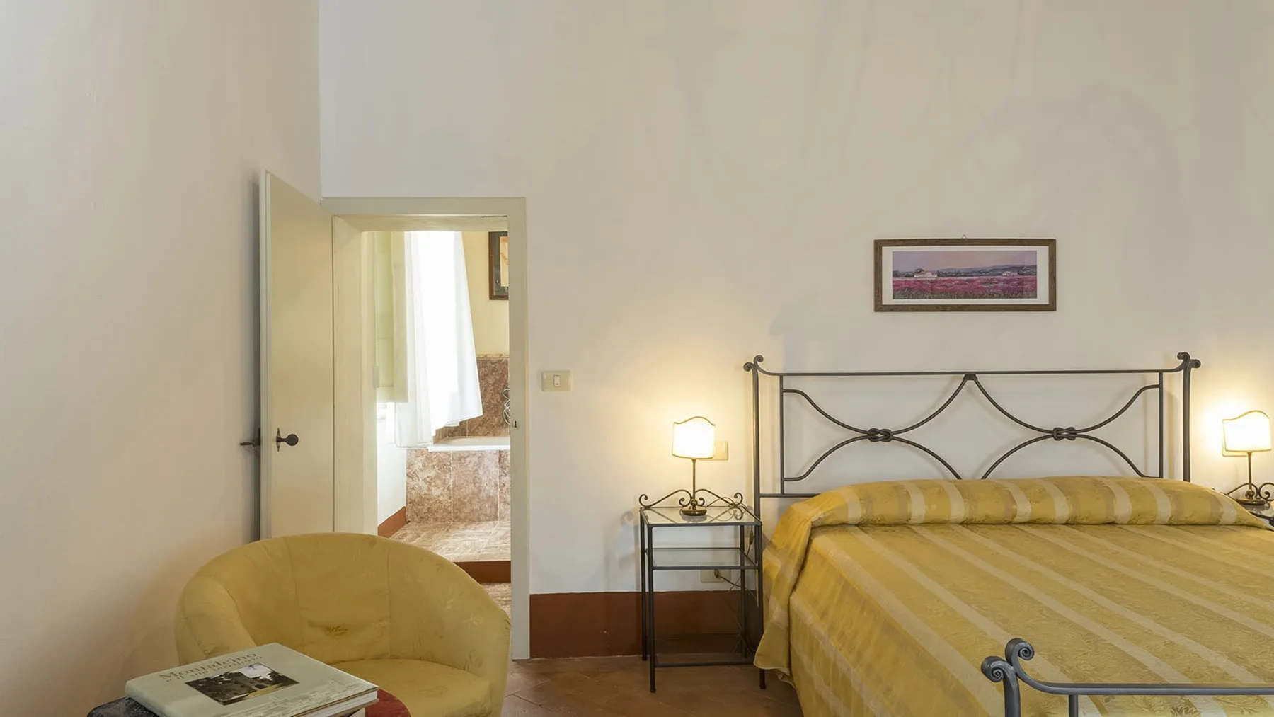 Un dormitorio con una colcha amarilla, mesitas de noche y una puerta abierta.