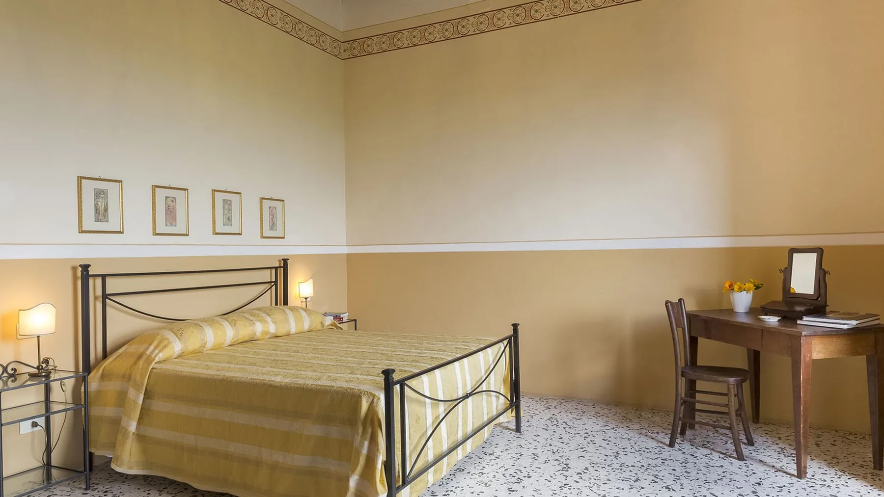 Un dormitorio con una colcha a rayas y un escritorio de madera junto a la pared.