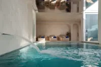 Espacio representativo del hotel: Una piscina cubierta de agua turquesa junto a una pared de vidrio.