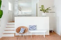 Espacio representativo del hotel: Una sala luminosa tiene un sofá blanco, una mesa pequeña y escaleras.