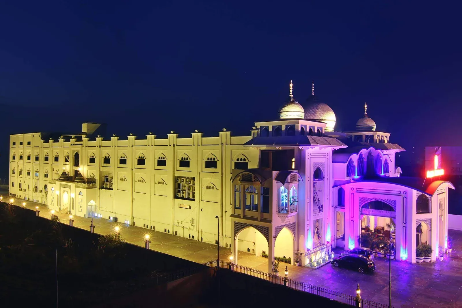 Espacio representativo del hotel: Un gran edificio iluminado por la noche, con una entrada arqueada muy iluminada.