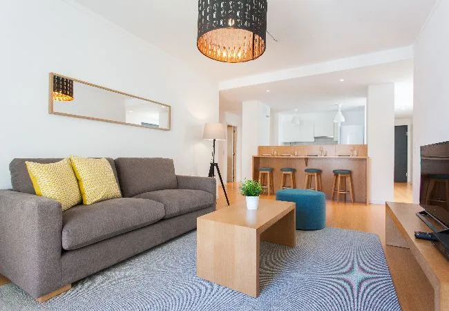 A living room with a gray sofa, coffee table, and open kitchen.