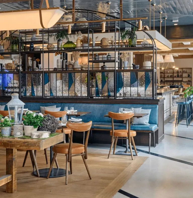 Representative hotel space: A restaurant dining area with tables, seating, and a long blue upholstered banquette.