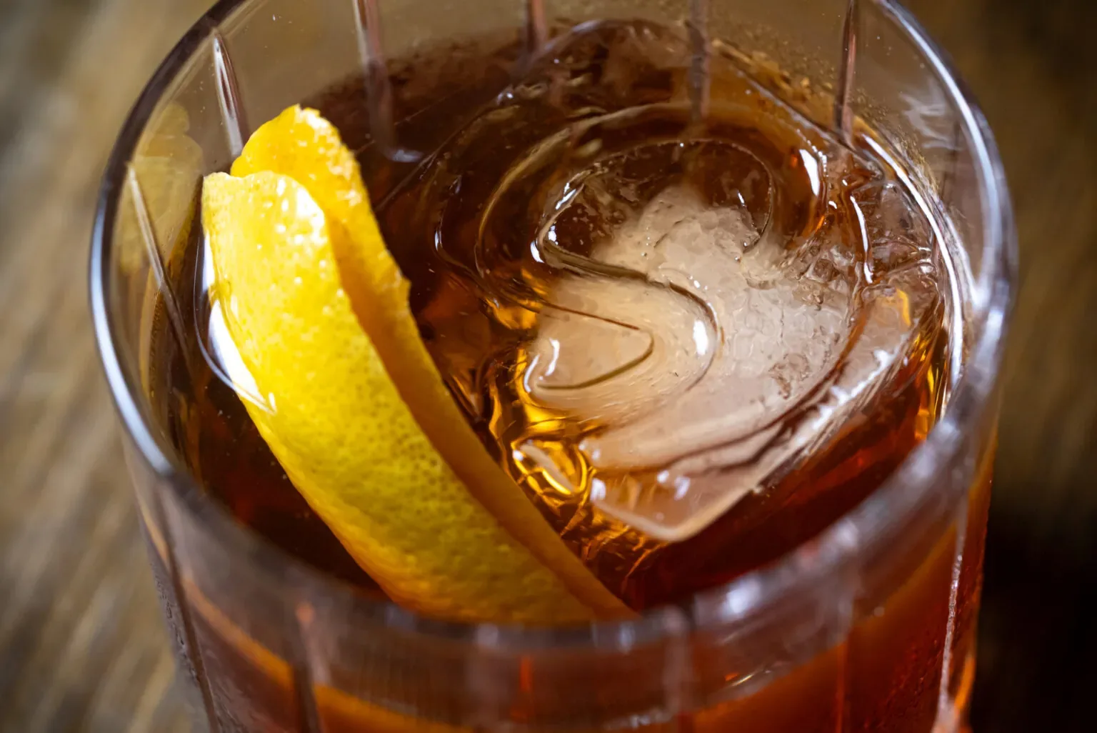Representative hotel space: A glass of amber-colored drink with ice and a lemon peel.