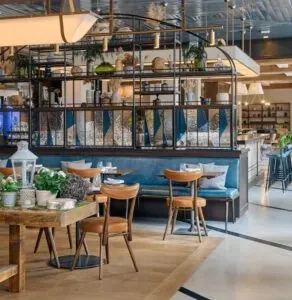 Representative hotel space: A hotel dining area with tables, seating, and a plant-filled divider.