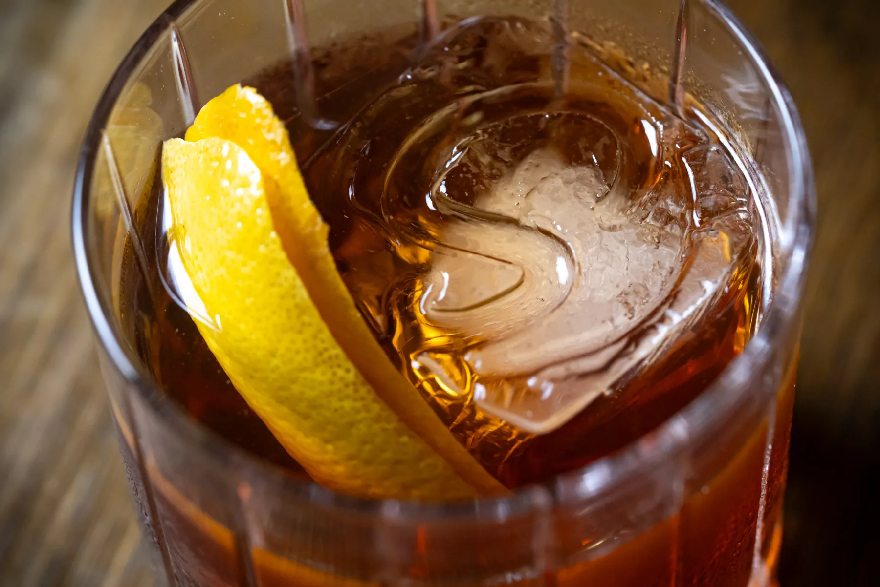Representative hotel space: A glass of amber-colored drink with ice and a lemon peel.