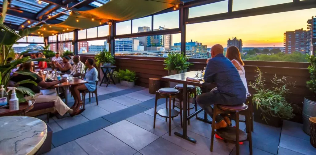 Representative hotel space: An open-air rooftop dining area overlooks the city at sunset.