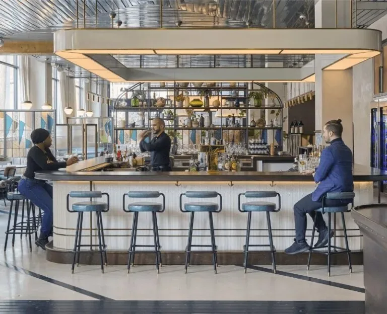 Representative hotel space: A modern bar counter with stools and shelving behind it.