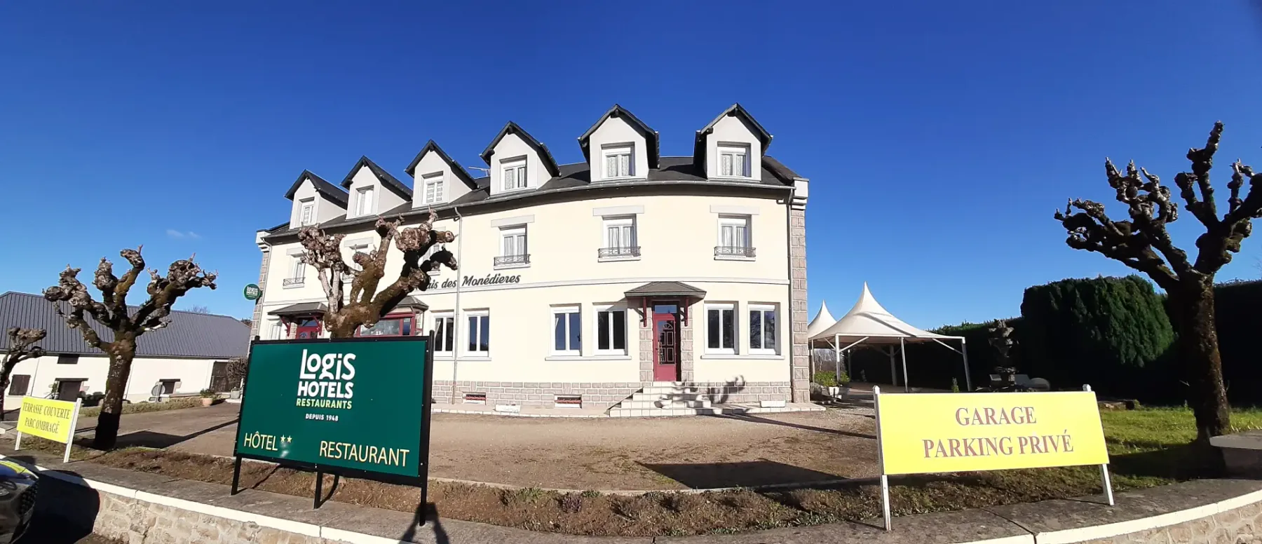 Representative hotel space: A hotel exterior with a green sign and a paved entrance.