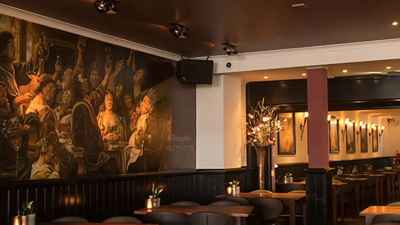 Espacio representativo del hotel: Comedor de restaurante con asientos oscuros y un gran mural en la pared.