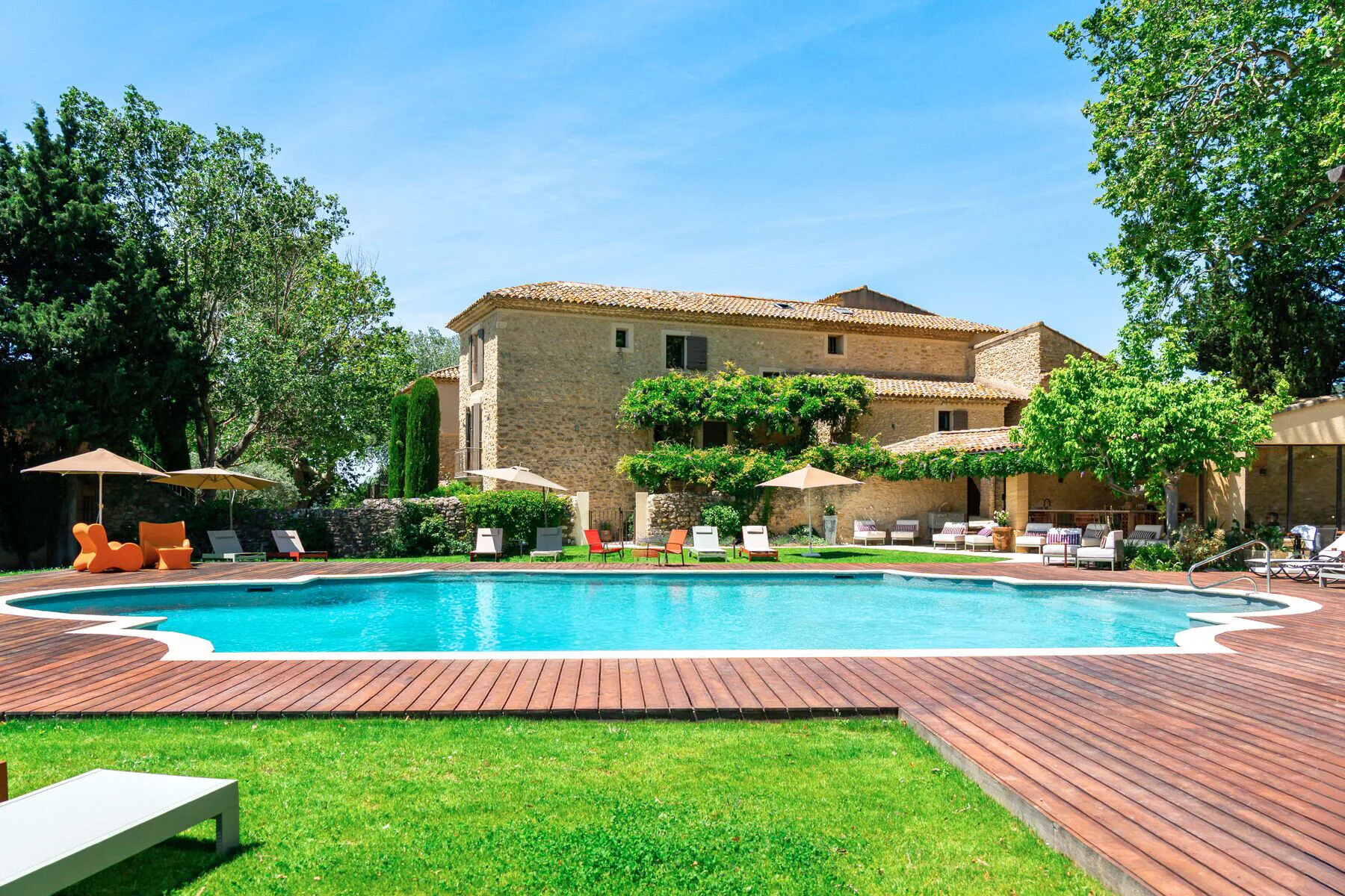 Representative hotel space: A swimming pool and wooden deck sit in front of a stone building.