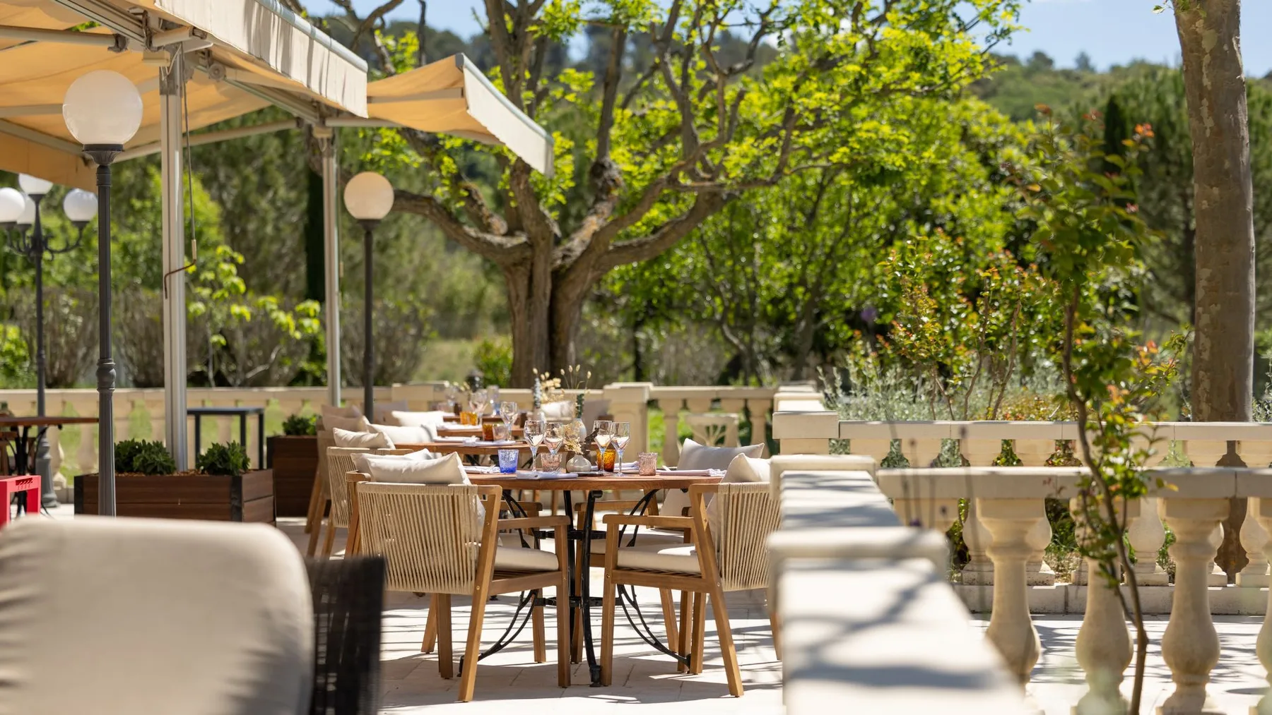 Representative hotel space: A shaded outdoor dining area with tables and seating beneath trees.