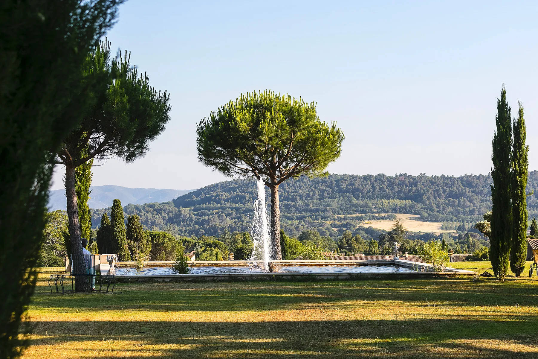 Representative hotel space: A landscaped garden with a fountain, trees, and wooded hills in the background.