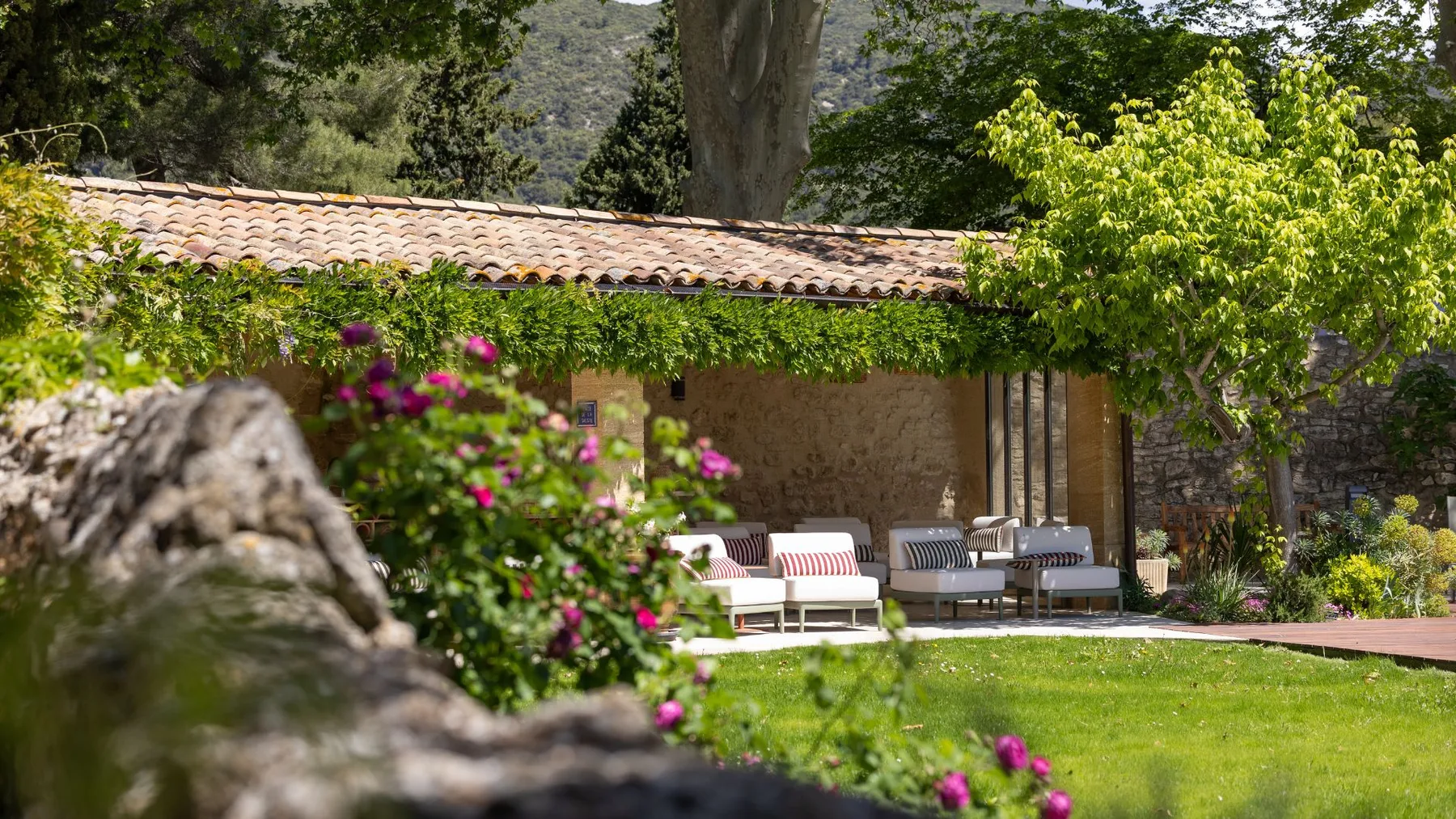 Representative hotel space: A garden patio with outdoor seating beside a stone building.
