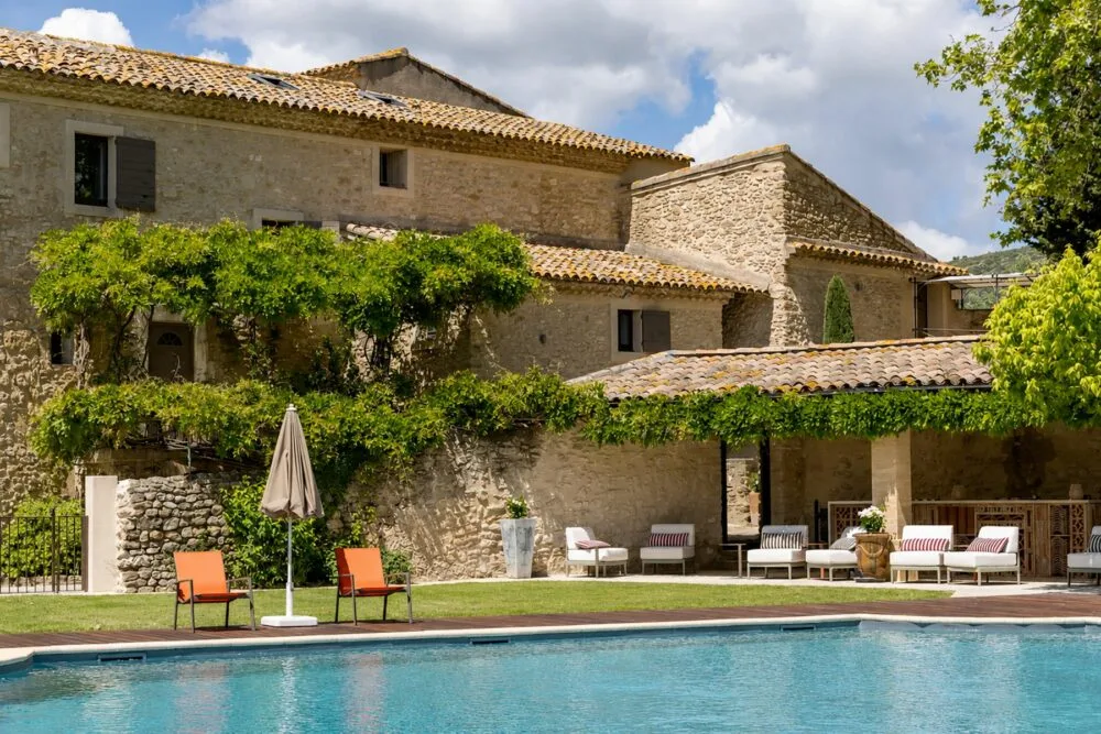 Representative hotel space: A stone building overlooks an outdoor pool and a patio with seating.