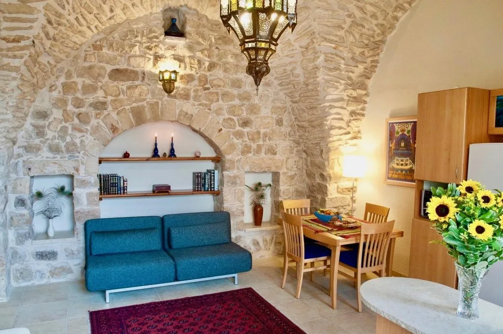 Representative hotel space: A stone-walled living area with blue seating and a dining table.