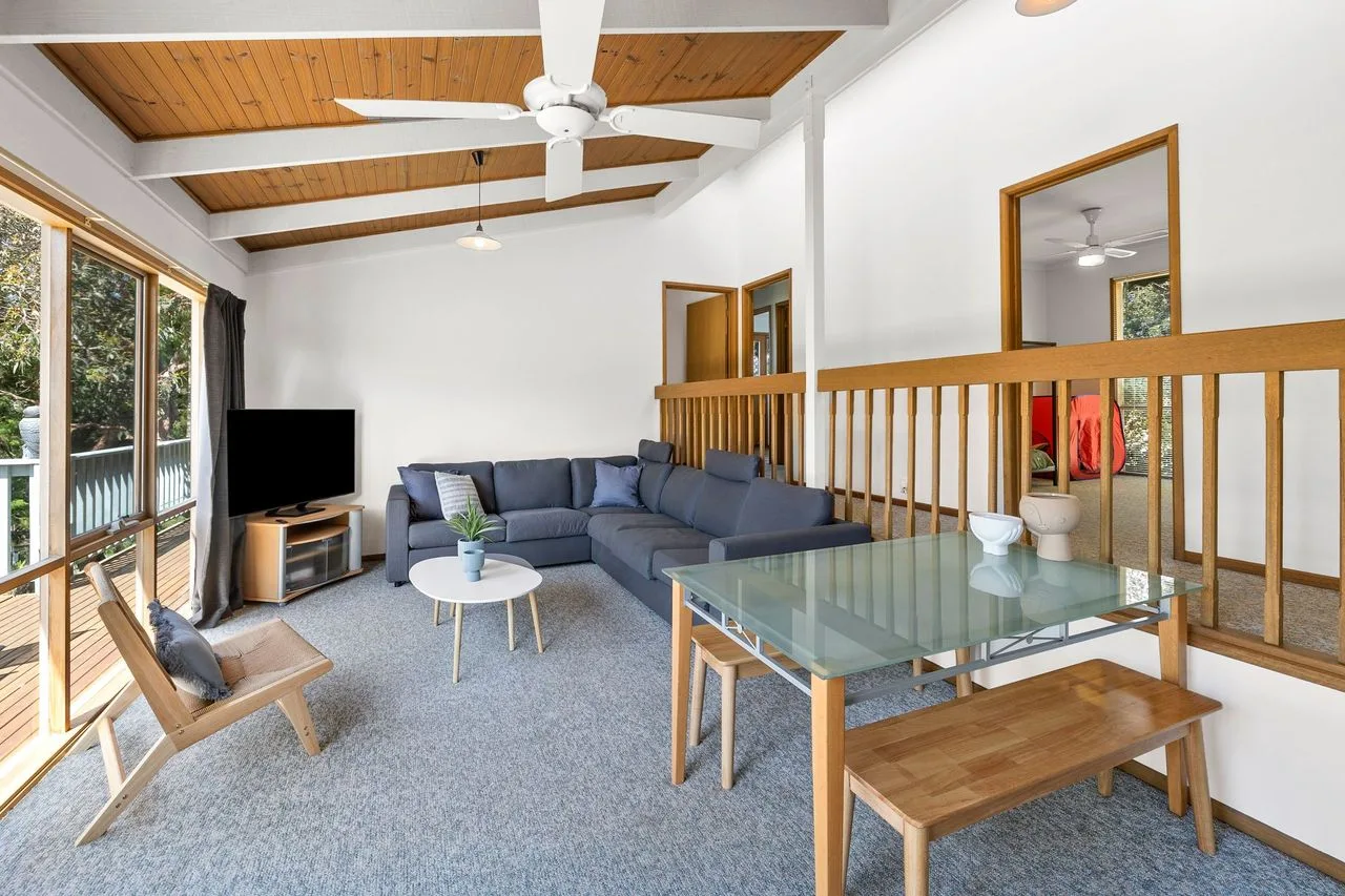 A living room with sectional seating, a television, and a glass coffee table.