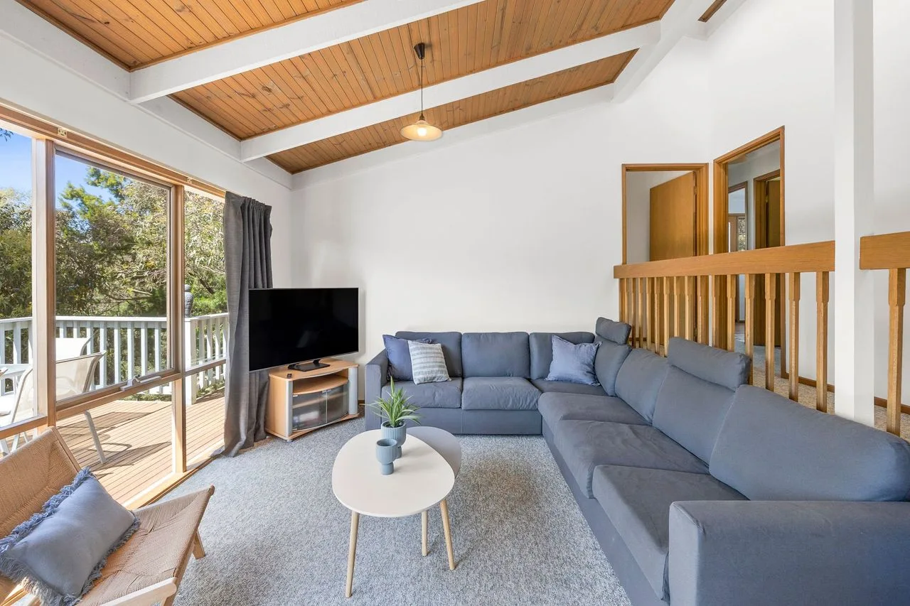 A bright living room with a large gray sectional sofa and sliding glass doors.