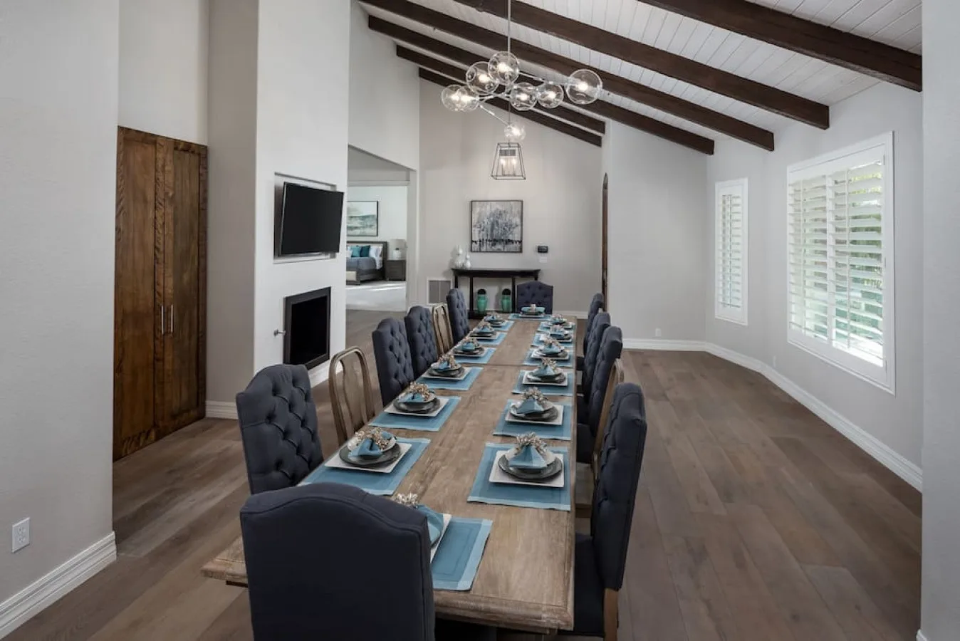 Un comedor con una mesa larga puesta con platos bajo vigas de techo expuestas.