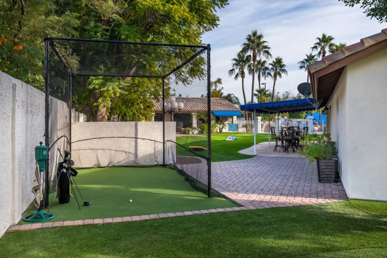 Un patio exterior y césped junto a un putting green con red.