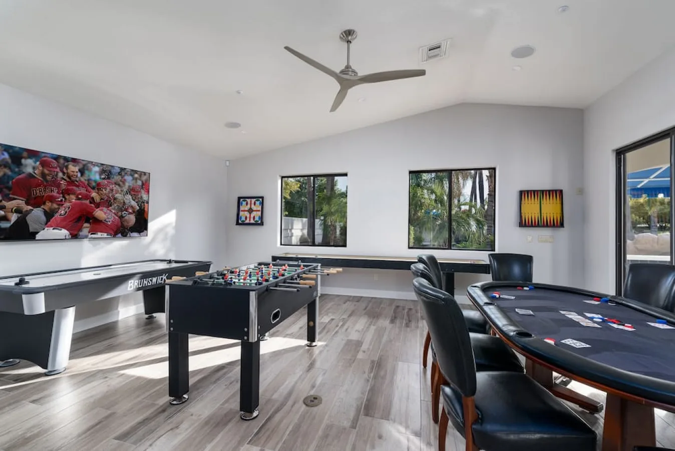 Una sala de juegos con mesa de billar, futbolín y televisor en la pared.