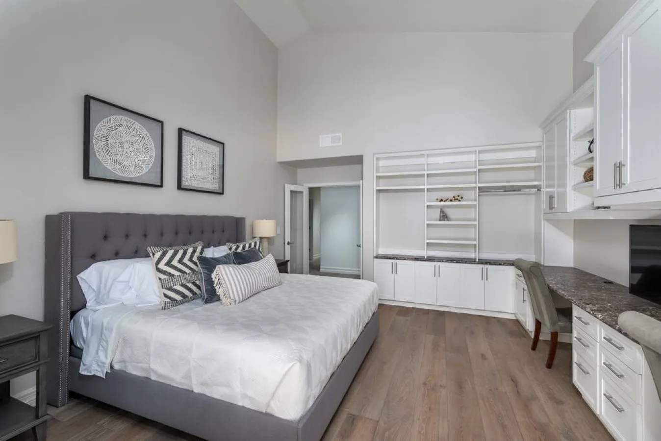 Un dormitorio con una cama grande, estanterías empotradas y una pequeña cocina a un lado.