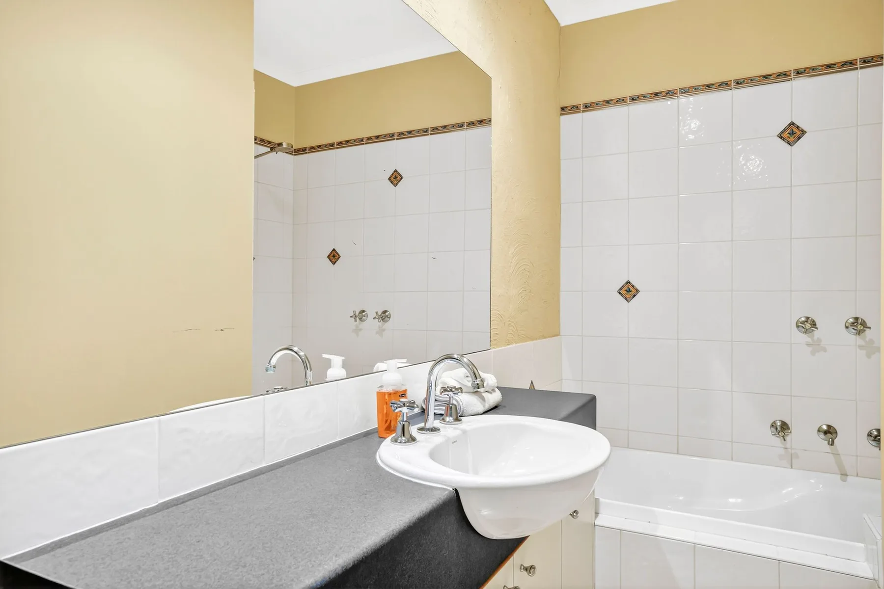 A bathroom with a sink and bathtub against tiled walls.