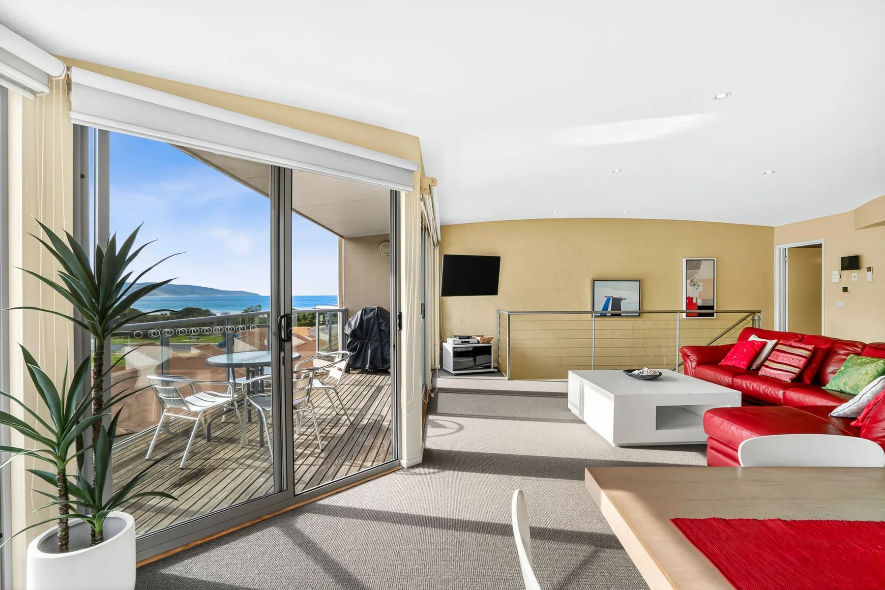 A bright living room opens onto a balcony through wide sliding glass doors.