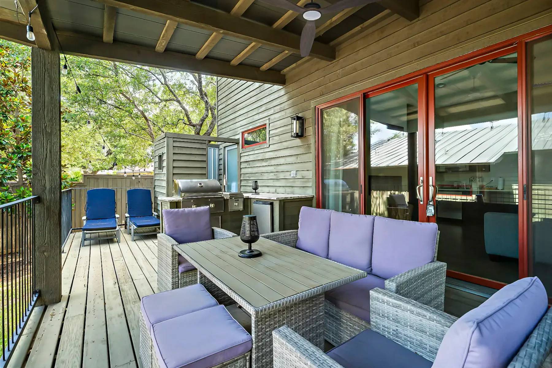 Una zona de estar exterior cubierta con una mesa junto a grandes puertas de vidrio.