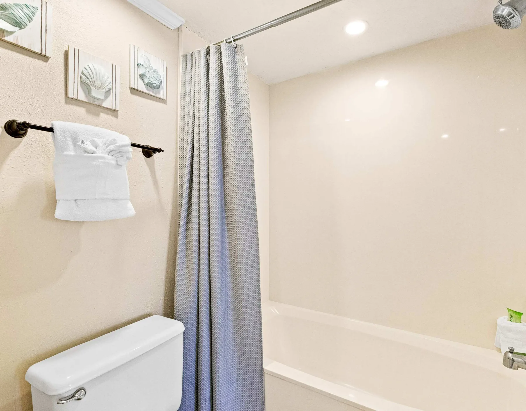 Un baño con bañera, cortina de ducha y una toalla colgada en la pared.