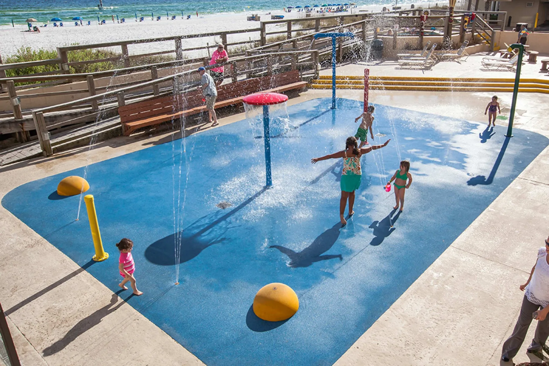 Zona común: Una zona de juegos acuáticos poco profunda con niños bajo chorros de agua.