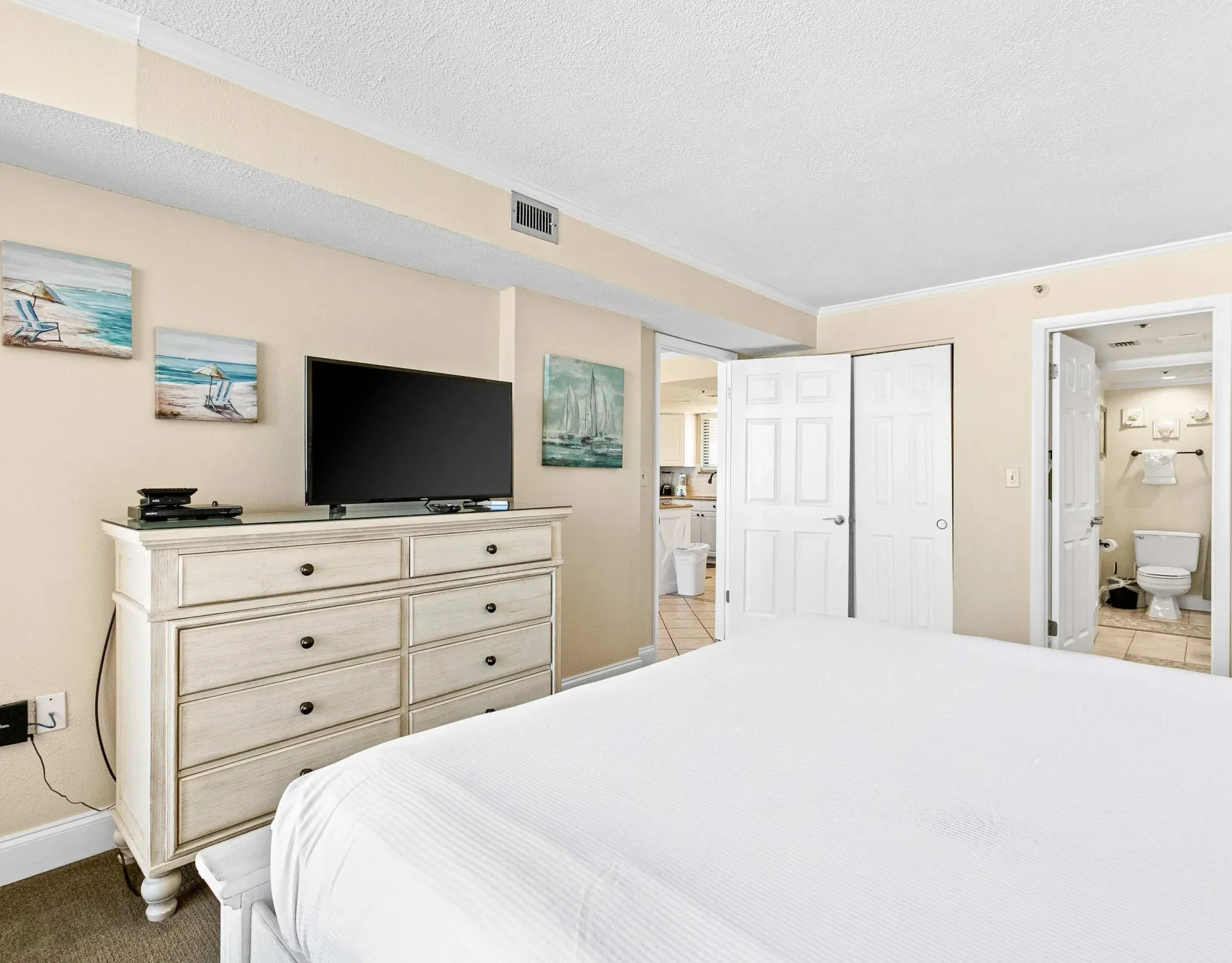 Un dormitorio con una cama grande, una cómoda y un televisor.