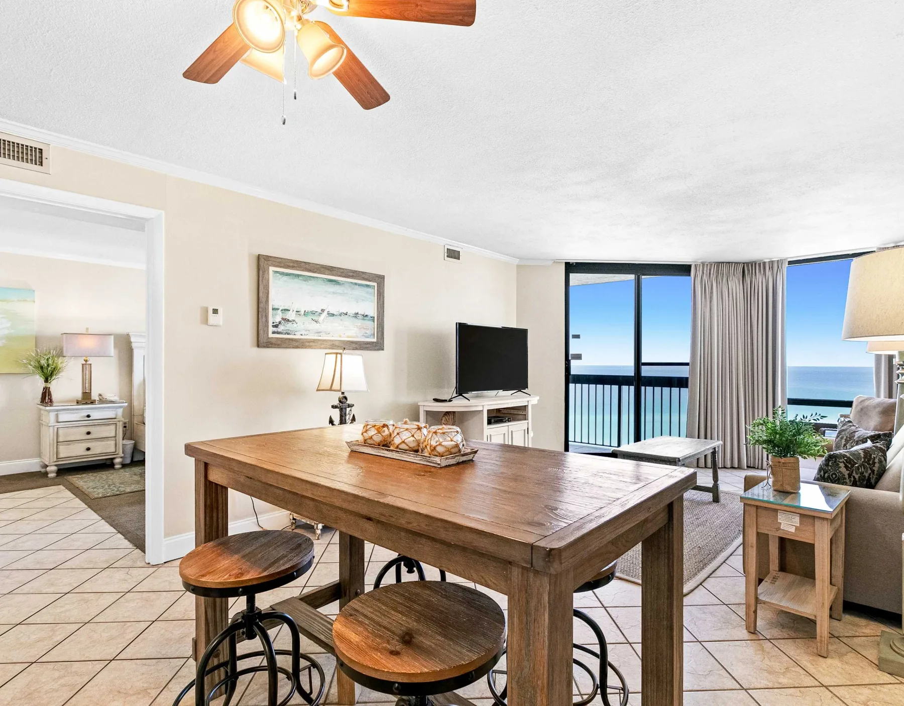 Comedor con una mesa de madera y asientos junto a grandes ventanas con vistas al agua.
