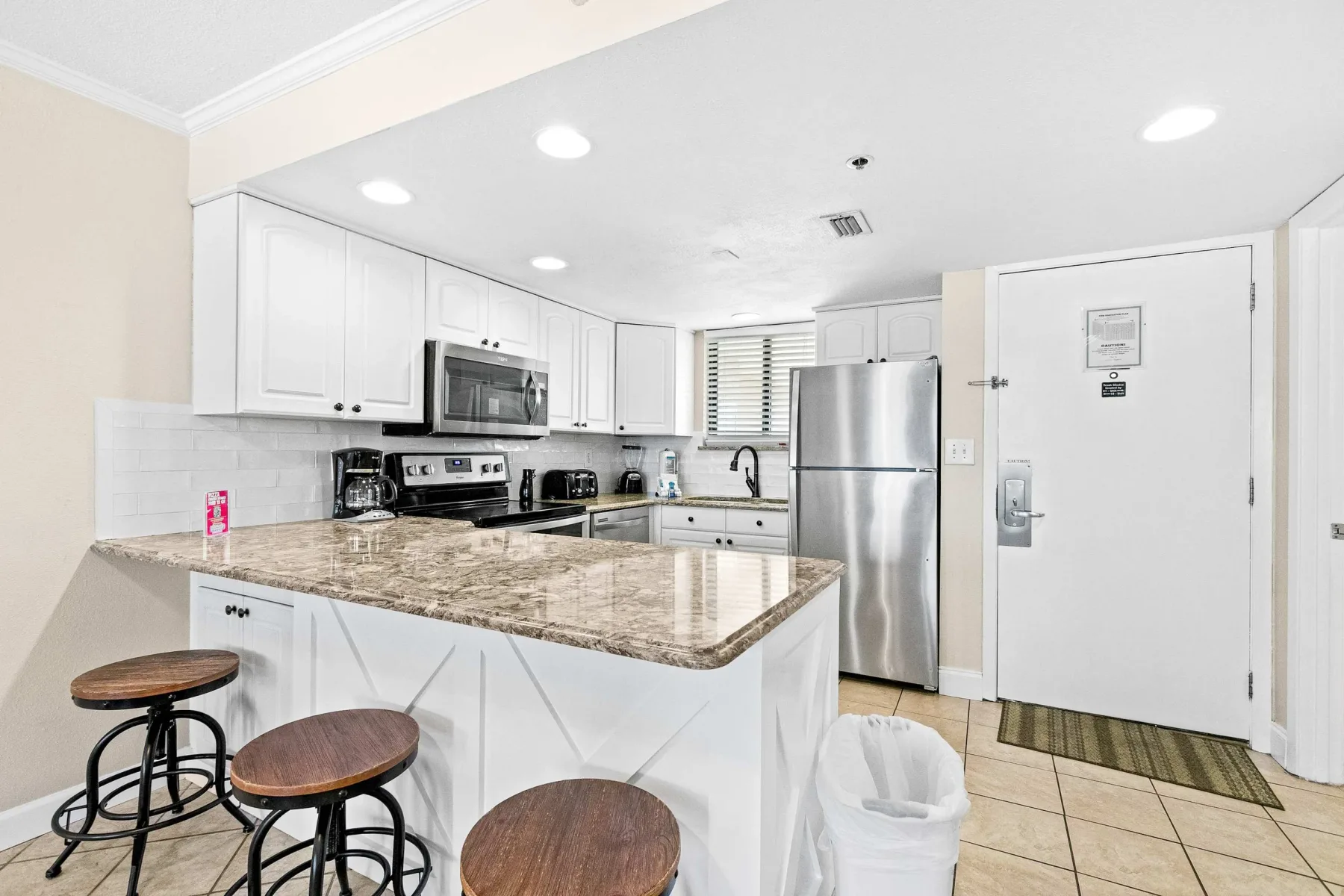 Una cocina luminosa con gabinetes blancos y una isla grande con superficie jaspeada.