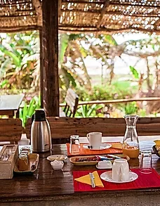 Representative hotel space: A dining table beneath a thatched roof overlooks lush greenery.
