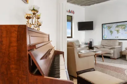 Representative hotel space: A living room with an upright piano and seating around a coffee table.