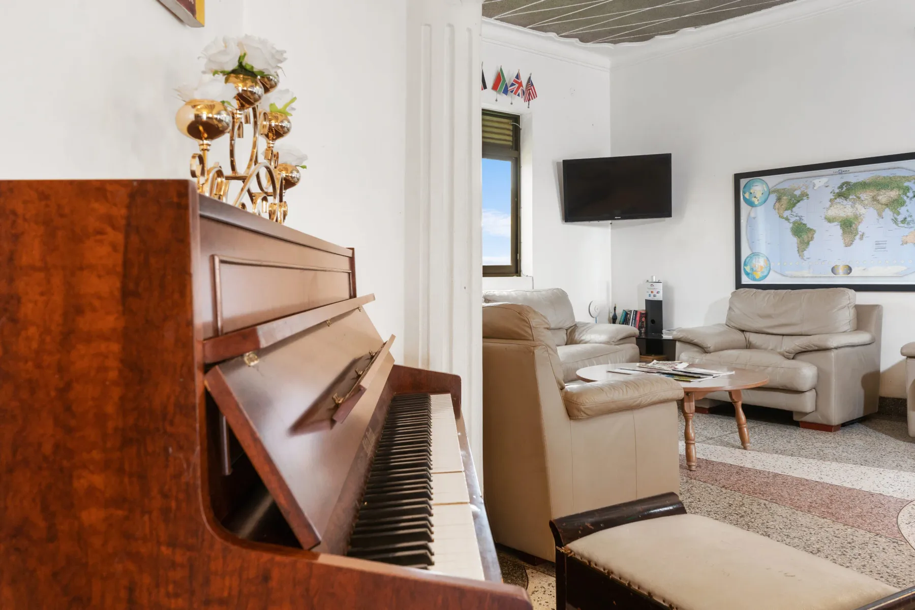 Representative hotel space: A living room with an upright piano and seating around a coffee table.