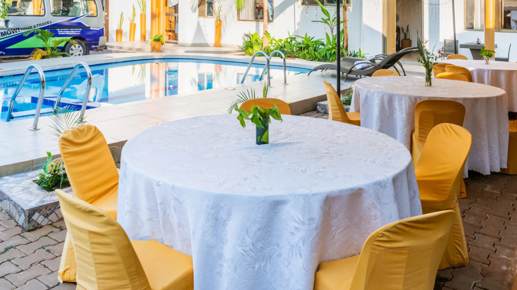 Representative hotel space: A dining area with round tables beside a swimming pool.