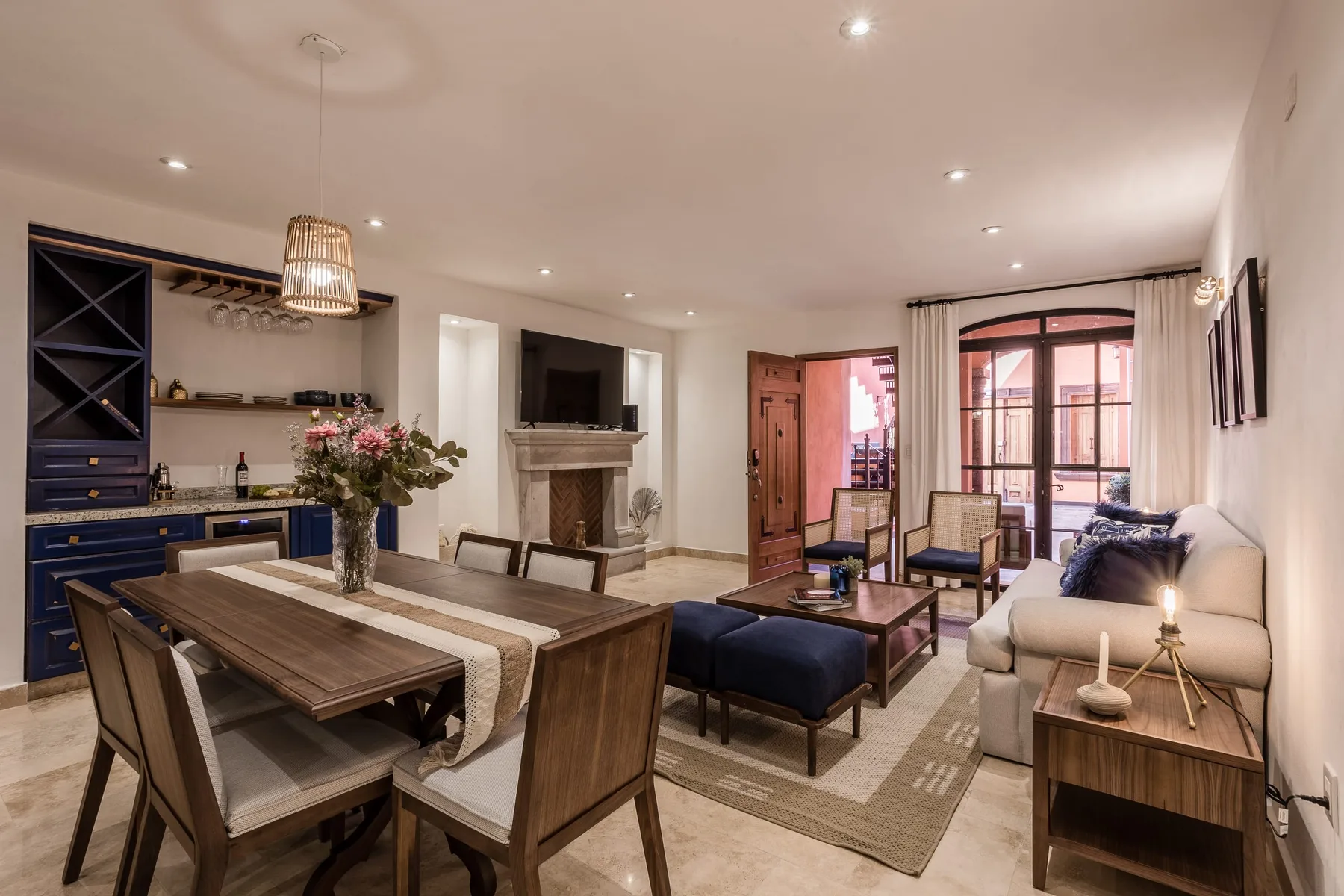 A bright living and dining room with a fireplace and large windows.